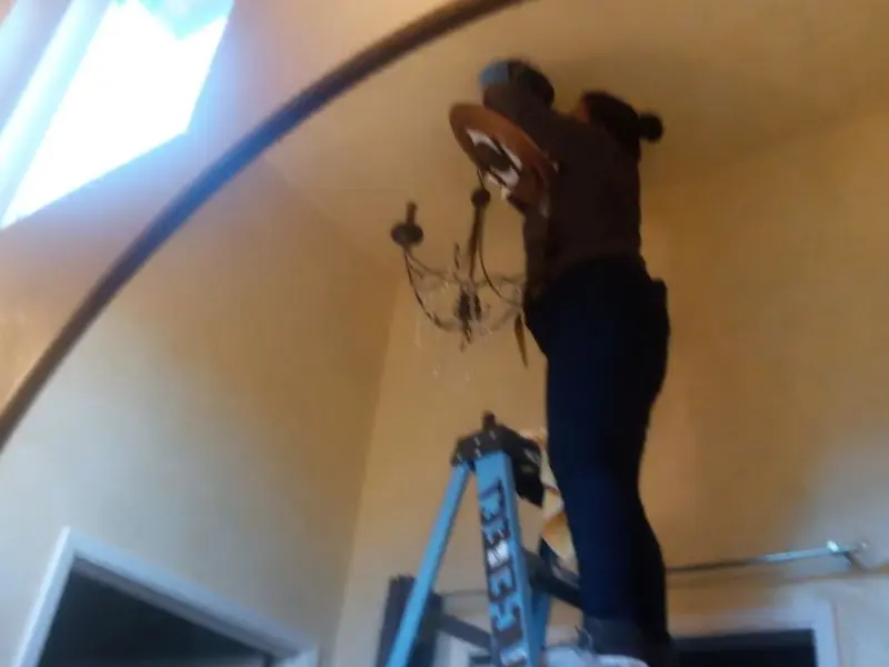 Electrician installing a chandelier in a Sioux Falls residence